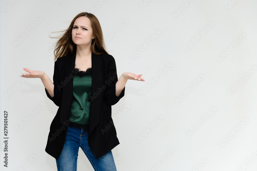 Concept portrait above the knee of a pretty girl, a young woman with long beautiful brown hair and a black jacket and blue jeans on a white background. In studio in different poses showing emotions. Concept portrait above the knee of a pretty girl, a young woman with long beautiful brown hair and a black jacket and blue jeans on a white background. In studio in different poses showing emotions.