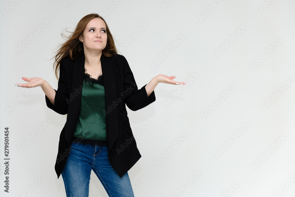 Concept portrait above the knee of a pretty girl, a young woman with long beautiful brown hair and a black jacket and blue jeans on a white background. In studio in different poses showing emotions. Concept portrait above the knee of a pretty girl, a young woman with long beautiful brown hair and a black jacket and blue jeans on a white background. In studio in different poses showing emotions.