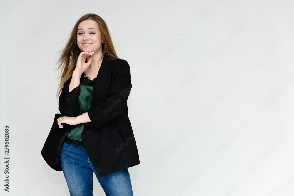 Concept portrait above the knee of a pretty girl, a young woman with long beautiful brown hair and a black jacket and blue jeans on a white background. In studio in different poses showing emotions. Concept portrait above the knee of a pretty girl, a young woman with long beautiful brown hair and a black jacket and blue jeans on a white background. In studio in different poses showing emotions.