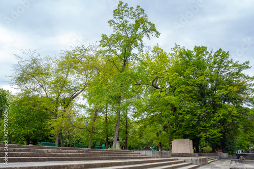 Lush green trees with concrete stairs in public park with cloudy sky, Geneva, Switzerland