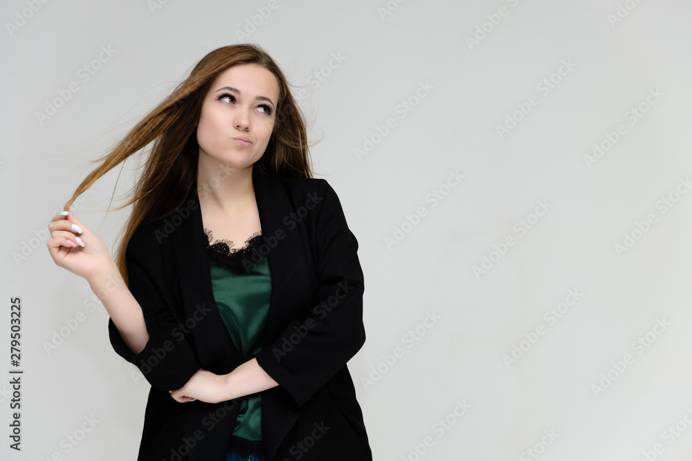 Concept portrait for the waist of a pretty girl, a young woman with long beautiful brown hair and a black jacket and blue jeans on a white background. In studio in different poses showing emotions. Concept portrait for the waist of a pretty girl, a young woman with long beautiful brown hair and a black jacket and blue jeans on a white background. In studio in different poses showing emotions.