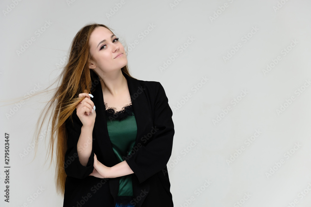 Concept portrait for the waist of a pretty girl, a young woman with long beautiful brown hair and a black jacket and blue jeans on a white background. In studio in different poses showing emotions.