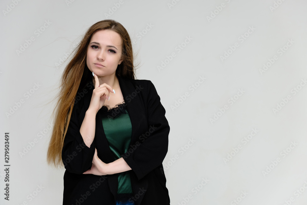 Concept portrait for the waist of a pretty girl, a young woman with long beautiful brown hair and a black jacket and blue jeans on a white background. In studio in different poses showing emotions. Concept portrait for the waist of a pretty girl, a young woman with long beautiful brown hair and a black jacket and blue jeans on a white background. In studio in different poses showing emotions.
