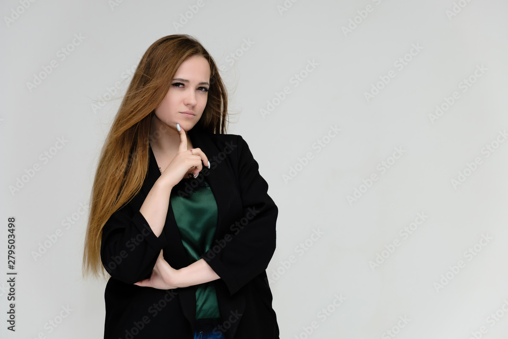 Concept portrait for the waist of a pretty girl, a young woman with long beautiful brown hair and a black jacket and blue jeans on a white background. In studio in different poses showing emotions.