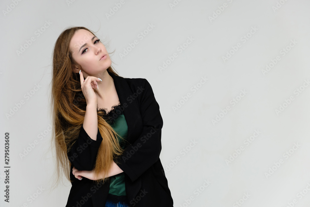 Concept portrait for the waist of a pretty girl, a young woman with long beautiful brown hair and a black jacket and blue jeans on a white background. In studio in different poses showing emotions. Concept portrait for the waist of a pretty girl, a young woman with long beautiful brown hair and a black jacket and blue jeans on a white background. In studio in different poses showing emotions.