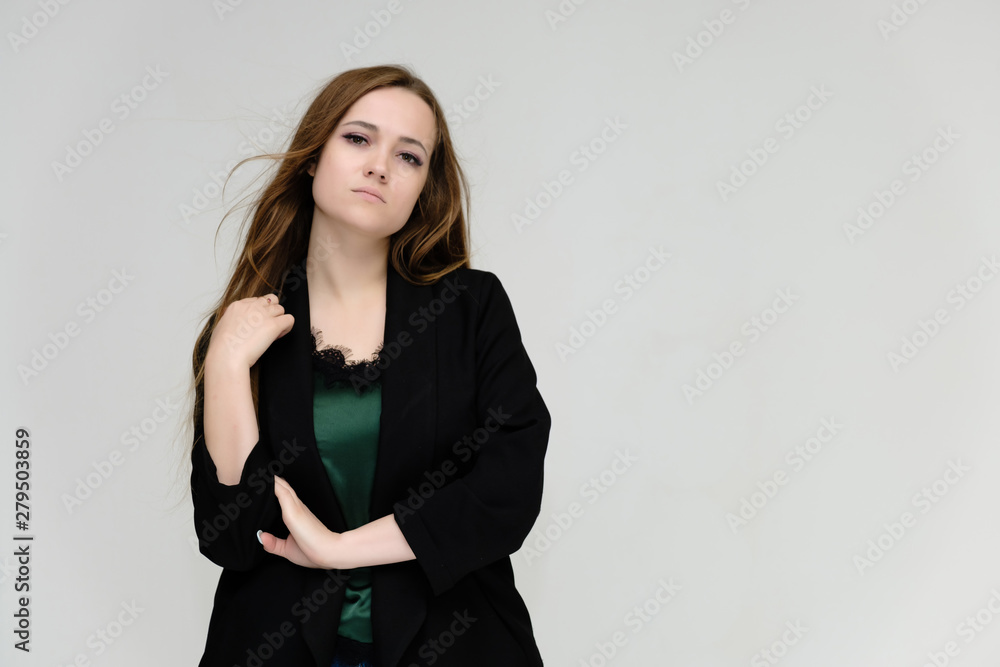 Concept portrait for the waist of a pretty girl, a young woman with long beautiful brown hair and a black jacket and blue jeans on a white background. In studio in different poses showing emotions. Concept portrait for the waist of a pretty girl, a young woman with long beautiful brown hair and a black jacket and blue jeans on a white background. In studio in different poses showing emotions.
