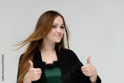 Concept close-up portrait of a pretty girl, a young woman with long beautiful brown hair and a black jacket on a white background. In the studio in different poses showing emotions.