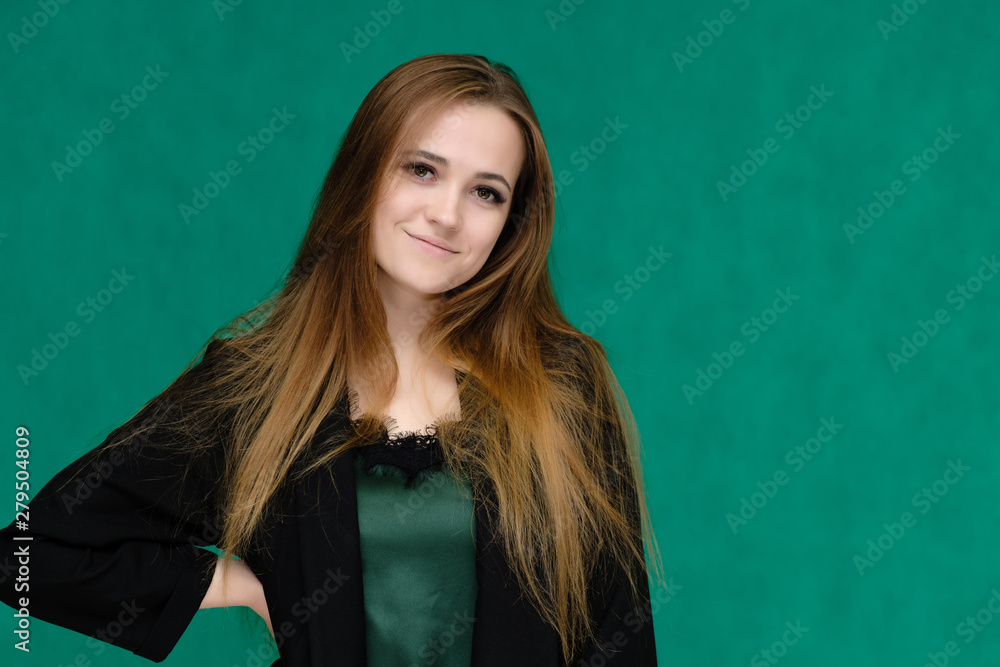Concept close-up portrait of a pretty girl, a young woman with long beautiful brown hair and in a black jacket on a green background. In the studio in different poses showing emotions. Concept close-up portrait of a pretty girl, a young woman with long beautiful brown hair and in a black jacket on a green background. In the studio in different poses showing emotions.