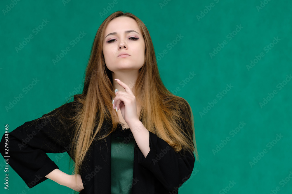 Concept close-up portrait of a pretty girl, a young woman with long beautiful brown hair and in a black jacket on a green background. In the studio in different poses showing emotions. Concept close-up portrait of a pretty girl, a young woman with long beautiful brown hair and in a black jacket on a green background. In the studio in different poses showing emotions.