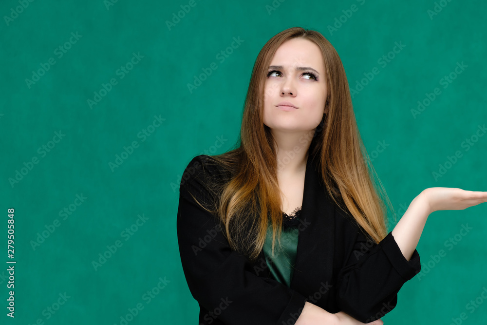 Concept close-up portrait of a pretty girl, a young woman with long beautiful brown hair and in a black jacket on a green background. In the studio in different poses showing emotions. Concept close-up portrait of a pretty girl, a young woman with long beautiful brown hair and in a black jacket on a green background. In the studio in different poses showing emotions.