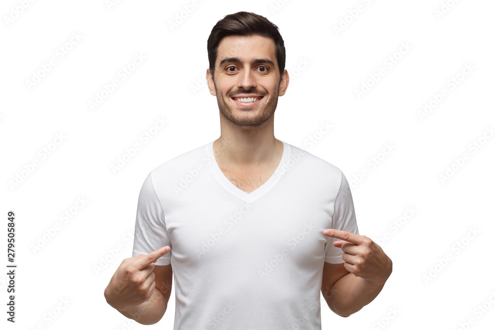 Young man is pointing to his blank t-shirt with index fingers, showing empty space for your advertising text or logo, standing isolated on white background Young man is pointing to his blank t-shirt with index fingers, showing empty space for your advertising text or logo, standing isolated on white background