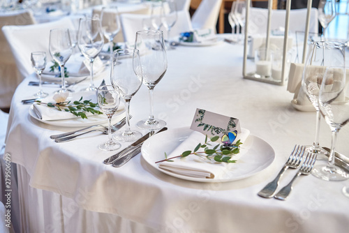 Table setting with blank guest card on empty white plate and cutlery on table, copy space. Menu mockup, place setting at wedding reception. Table served for wedding banquet in restauran