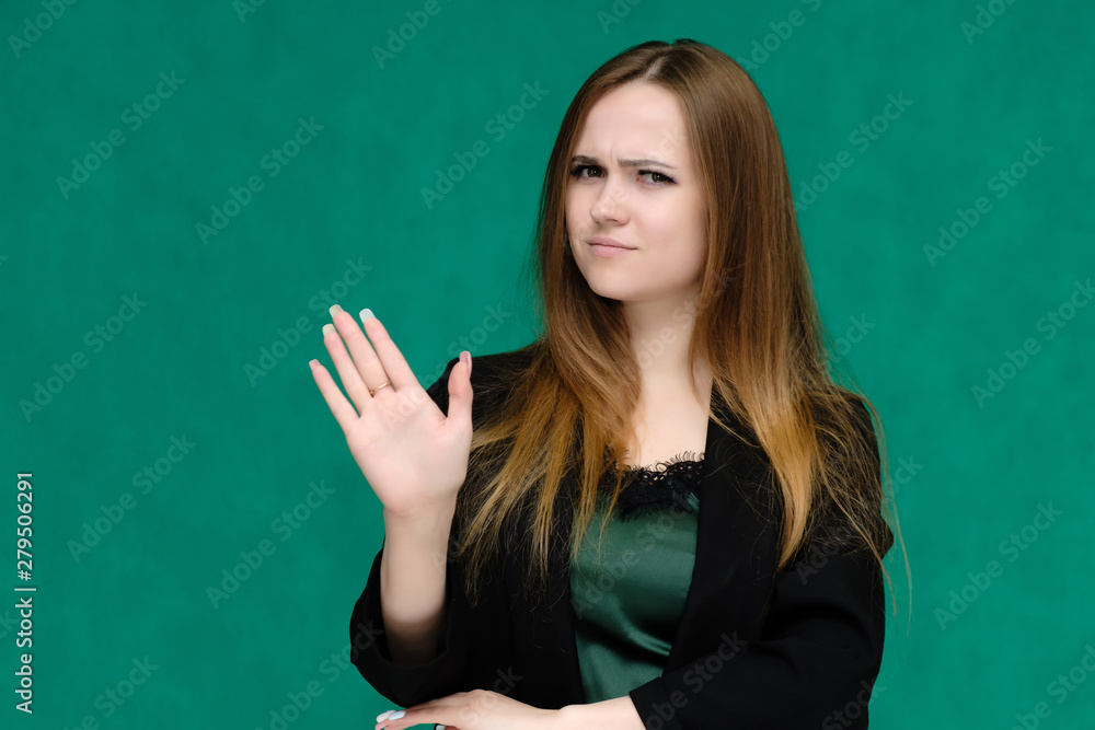 Concept close-up portrait of a pretty girl, a young woman with long beautiful brown hair and in a black jacket on a green background. In the studio in different poses showing emotions. Concept close-up portrait of a pretty girl, a young woman with long beautiful brown hair and in a black jacket on a green background. In the studio in different poses showing emotions.