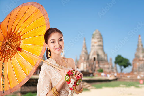 Thai asian women welcome with traditional Thai suit and umbrella on temple background, hello Sawadee thailand travel concept