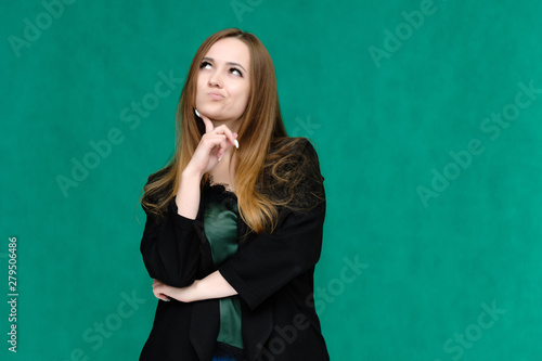 Concept portrait for a belt of a pretty girl, young woman with beautiful brown hair and in a black jacket and green T-shirt on a green background. In the studio in different poses showing emotions. © Вячеслав Чичаев