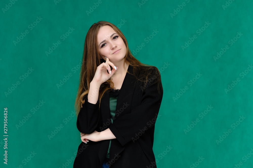 Concept portrait for a belt of a pretty girl, young woman with beautiful brown hair and in a black jacket and green T-shirt on a green background. In the studio in different poses showing emotions.