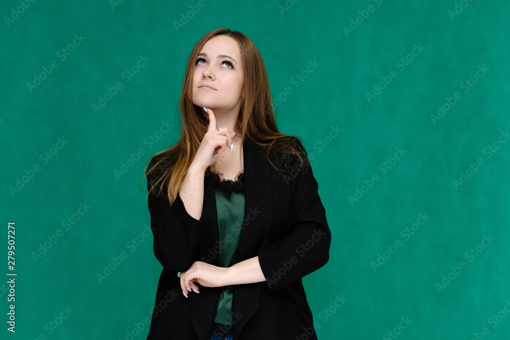 Concept portrait for a belt of a pretty girl, young woman with beautiful brown hair and in a black jacket and green T-shirt on a green background. In the studio in different poses showing emotions. Concept portrait for a belt of a pretty girl, young woman with beautiful brown hair and in a black jacket and green T-shirt on a green background. In the studio in different poses showing emotions.