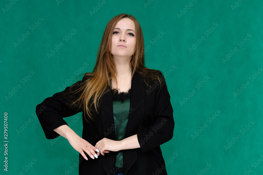 Concept portrait for a belt of a pretty girl, young woman with beautiful brown hair and in a black jacket and green T-shirt on a green background. In the studio in different poses showing emotions. Concept portrait for a belt of a pretty girl, young woman with beautiful brown hair and in a black jacket and green T-shirt on a green background. In the studio in different poses showing emotions.
