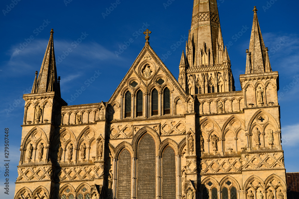 Great West Front facade of Salisbury Cathedral with statuary of Saints and Angels in gold evening light in Salisbury England