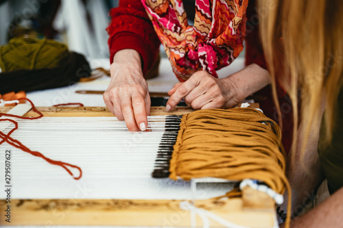 Woman demonstrating weaving on a hand loom