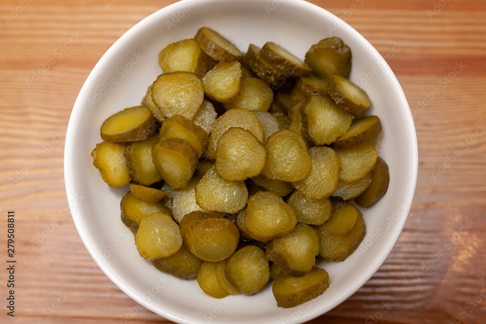 Sliced gherkins cucumbers in a bowl on a wooden table Sliced gherkins cucumbers in a bowl on a wooden table