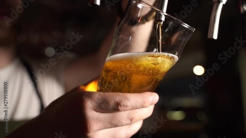 Bartender pouring beer into glass with bubbles close up