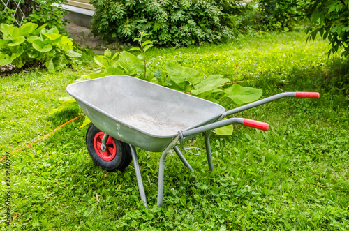 garden trolley with red handles and wheels stands on the grass