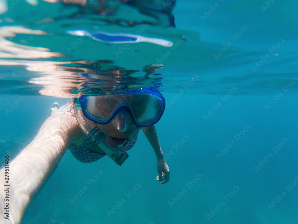 woman taking a selfie snorkeling in clear tropical waters - active holiday