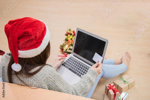 Woman hand holding credit card and doing shopping online near christmas tree at home.