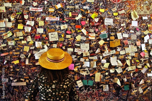 back view of Woman looking at the wall of of Juliet's house (Casa di Giulietta) are completely covered in graffiti, bolts and chewing gum with short message left by many visitors. tourist attraction photo