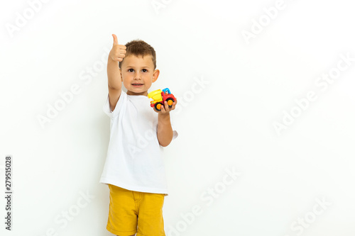 Portrait of a little boy laughing with thumbs up sign on gray background
