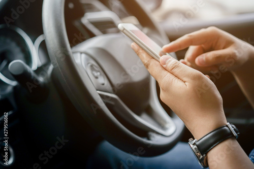 close up driver woman hand holding smartphone for using GPS navigation of travel destination and swipe for reading data on web browser or texting message online for contact while parking photo