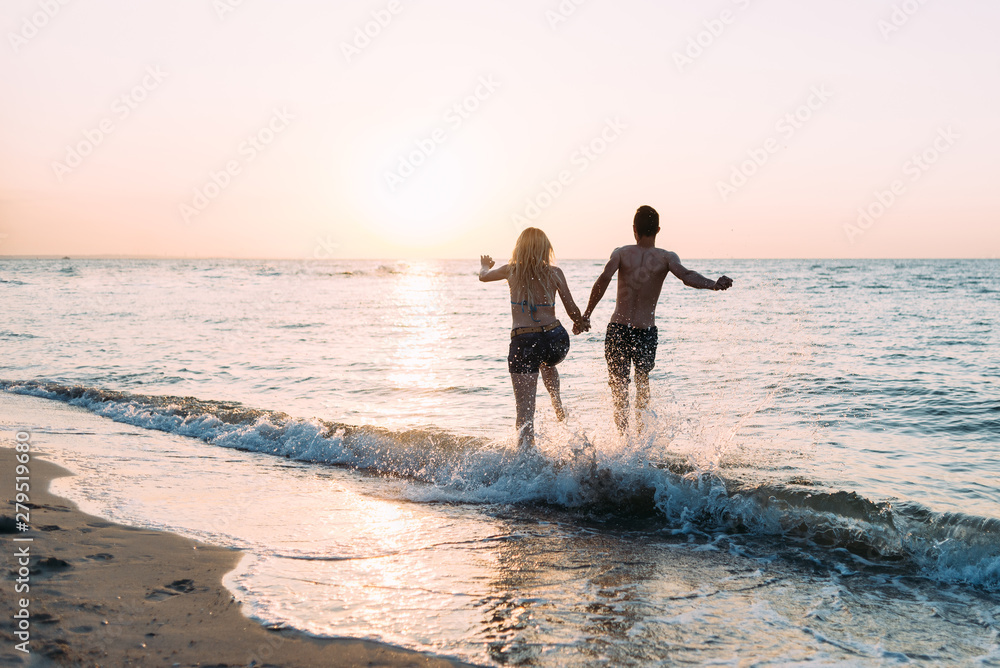 honeymoon on the ocean, a young couple in love fun runs on the water, a lot of spray