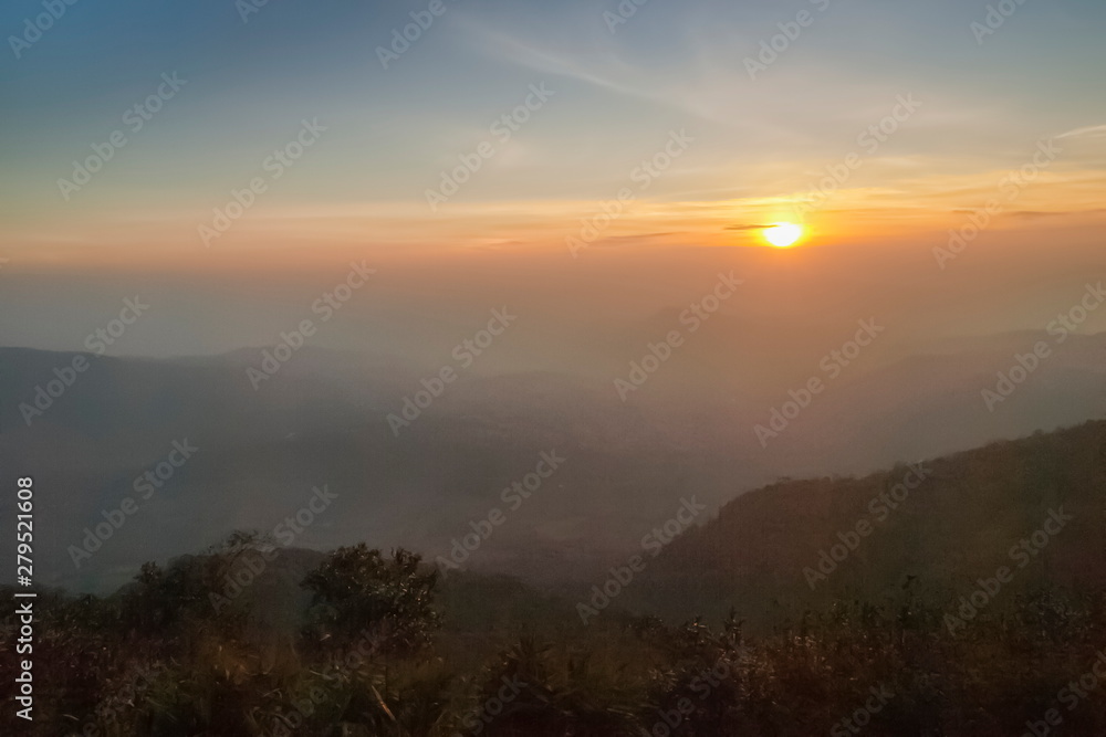 Obraz premium Mountain view morning of top hill around with soft fog and yellow sun light in the sky background, sunrise at top of Phu Ruea National Park, Phu Ruea District, Loei Province, Thailand.