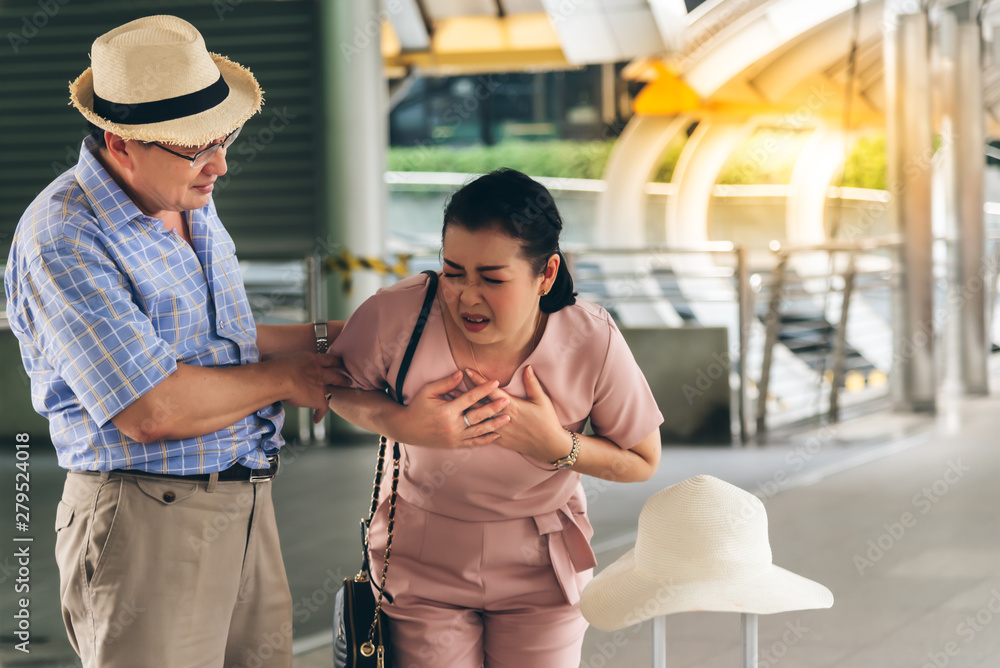 Naklejka premium The husband is worried about the Asian wife, are suffering from angina Due to heart disease, During travel, to elder and health concept.