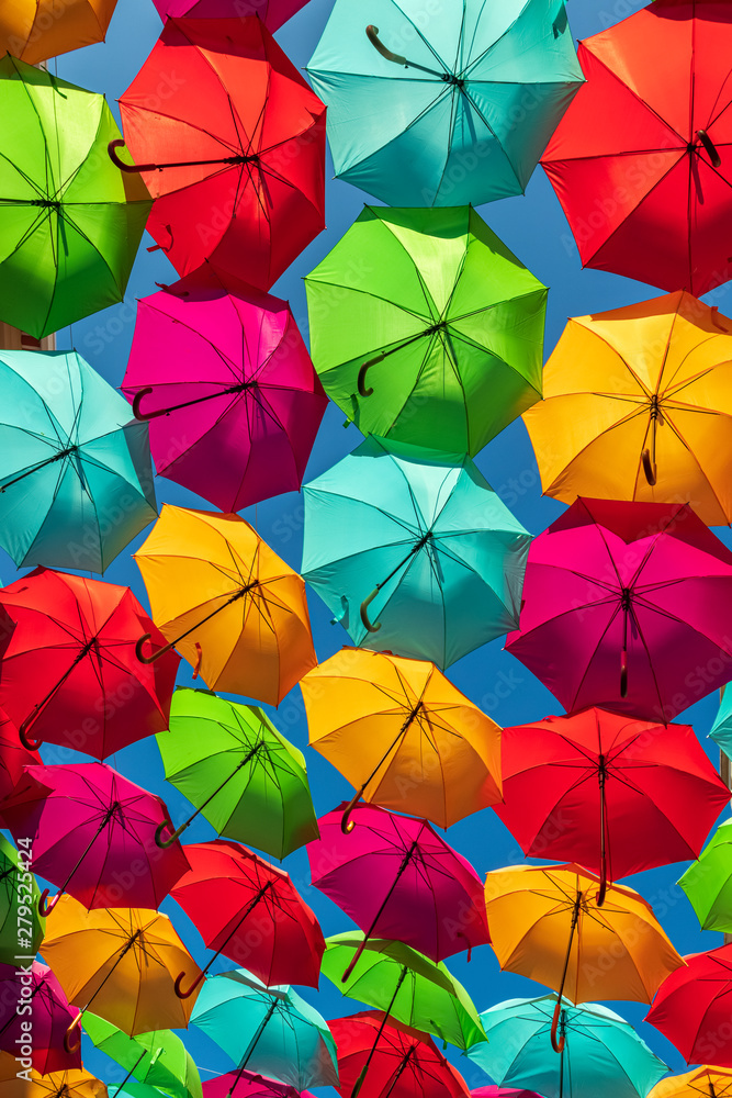 Naklejka premium Parasole w różnych kolorach tworzące wzór na tle błękitnego nieba.