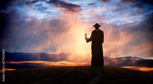 Fotografia pastor - priest on the hill at sunset with the cross