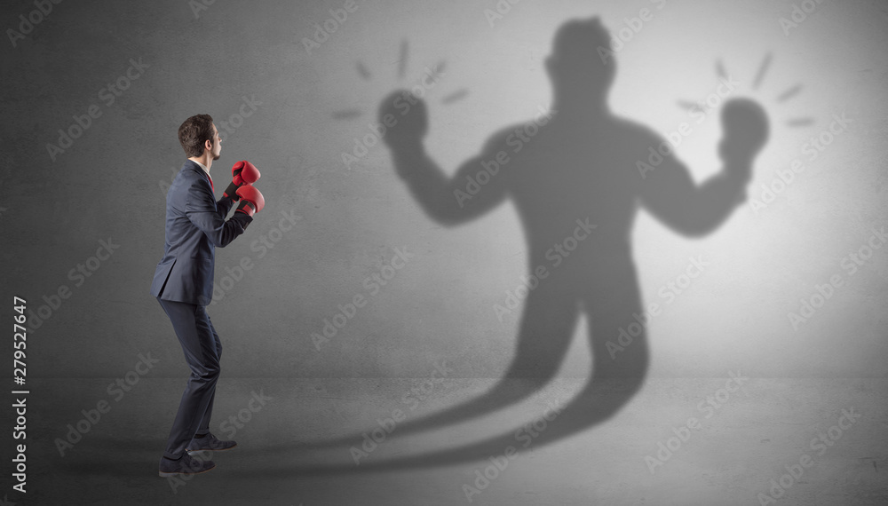 Businessman trying to fight with his unarmed shadow Businessman trying to fight with his unarmed shadow