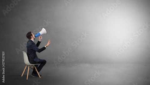 Canvas Print Businessman staying in an empty grey dark room with stuffs on his lap