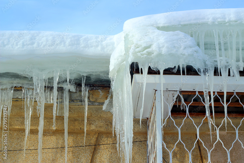 Icicles on the roof against the blue sky Icicles on the roof against the blue sky