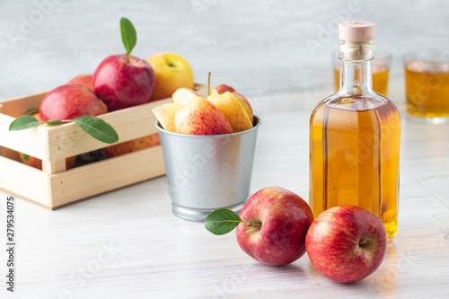 Healthy organic food. Apple cider vinegar or juice in glass bottle and fresh red apples on a light background.