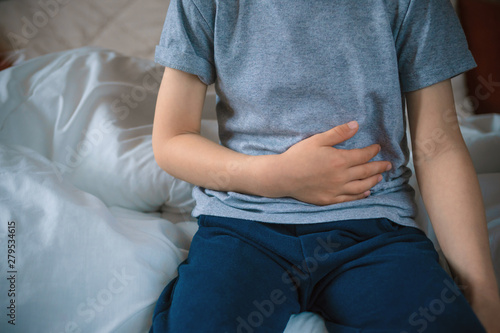 abdominal pain in a preschool child. poisoning in children. the boy holds his hands to the abdominal cavity