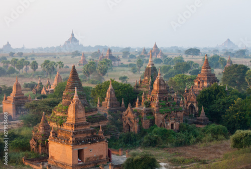 Orange mystical sunrise landscape view with silhouettes of old ancient temples and palm trees in dawn fog from balloon, Bagan, Myanmar. Burma