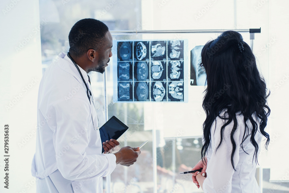Fototapeta premium Two doctors look at an x-ray and discuss the problem. Medical technicians pointing at MRI x-ray of patient. Radiologist checking x-ray. Medical and radiology concept.
