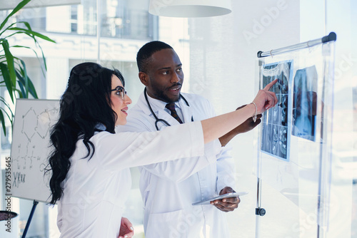 Two doctors look at an x-ray and discuss the problem. Medical technicians pointing at MRI x-ray of patient. Radiologist checking x-ray. Medical and radiology concept.
