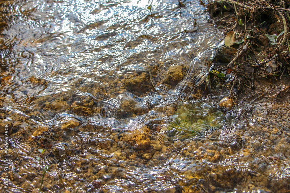 The sun shines on the flowing stream table, and the clear water can see the stones below. The sun shines on the flowing stream table, and the clear water can see the stones below.