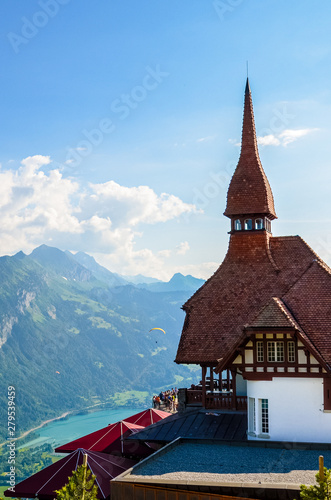 Beautiful top of Harder Kulm in Swiss Interlaken photographed in summer sunset with paragliders flying around. Turquoise Lake Thun in background. Alpine landscape. Travel destination