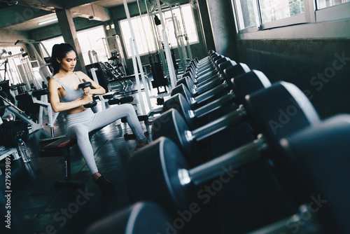 Healthy fitness women lifting dumbbell weight in gym