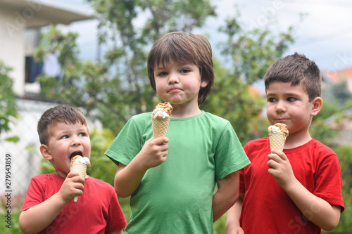 Three happy little boy eating ice cream. Closeup of children eating ice cream in the park