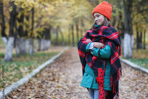 Young beautiful mother with her daughter on nature. A girl in a hat walks in the park. Girl in autumn city park in leaf fall.